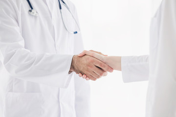 Doctors in lab coats greeting each other with handshake 