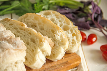 White wheat bread, Italian ciabatta, cut into pieces on a wooden board.Slices of white bread for sandwiches
