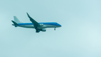 A blue plane flying and preparing to land, with the open landing train.