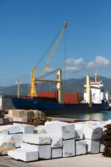 Carrara marble blocks for export and cargo ship at marina di carrara italy on a clear sunny day