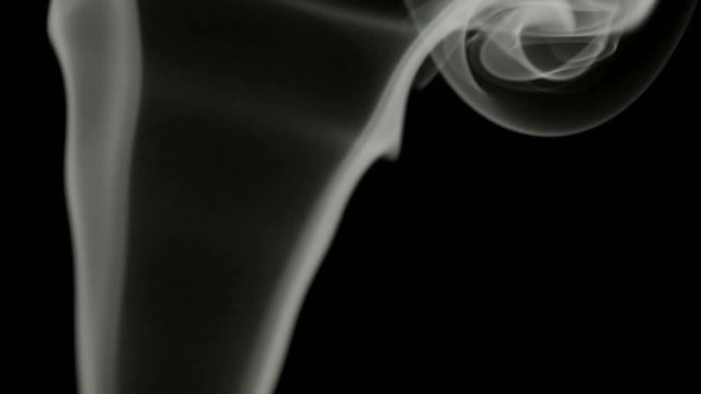 Thin trickle of gray smoke slowly rising graceful twists up on black background. Black and white smoke blowing from bottom to top. Closeup