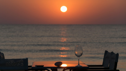 Fototapeta na wymiar stone and glass on a table with chairs and umbrella in reed, at sunrise at the Mediterranean Sea