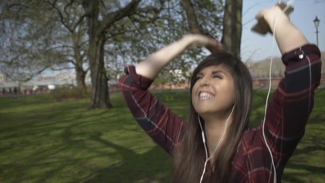 Attractive Caucasian female dancing to music in a park