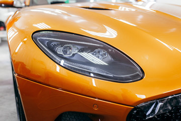 Orange modern car closeup on black background