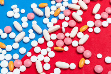 Multicolored pills on blue and red background. Medical concept. Texture.