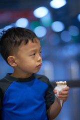young boy is eating melting cone icecream on bokeh background