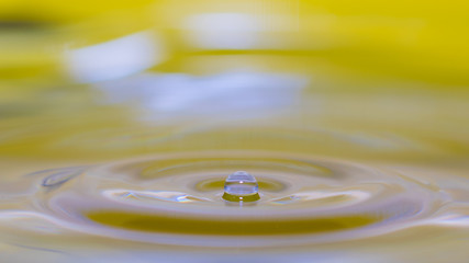 water splash in colorful background with a drop of water flying from above