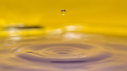 water splash in colorful background with a drop of water flying from above