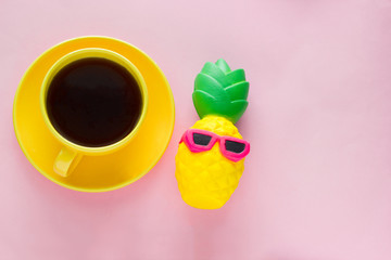 top view   yellow coffee mug and pineapple  squishy toy  on a pink background