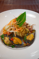 Spicy Seafood Spaghetti stir fried (Pad Cha) rolled in the fork on white dish of luxury restaurant