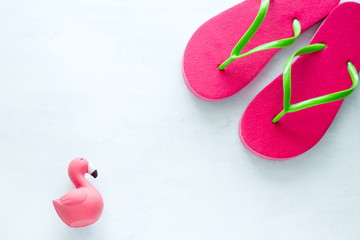 pink beach flip flops  and squishy toy  flamingo  on white  background copy space