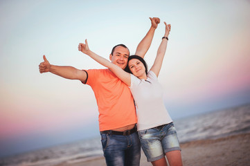 Young couple of lovers man and woman hug kiss and laughing on the seashore on sunset. Love near sea. Emotions Summer Lifestyle People Feelings Travel Anniversary