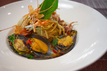 Spicy Seafood Spaghetti stir fried (Pad Cha) rolled in the fork on white dish of luxury restaurant