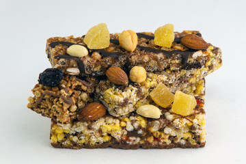 vegan dessert: several cereal bars with nuts, raisins and honey, on white, short focus