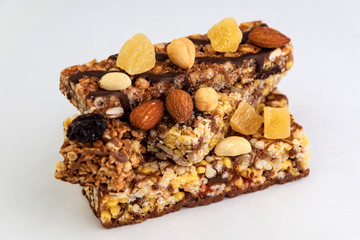 vegan dessert: several cereal bars with nuts, raisins and honey, on white, short focus