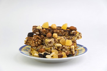 vegan dessert: several cereal bars with nuts, raisins and honey, in a colorful plate on white, short focus