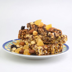 vegan dessert: several cereal bars with nuts, raisins and honey, in a colorful plate on white, short focus