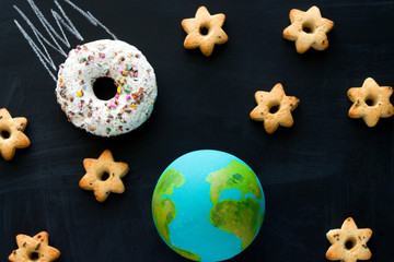 top view  handmade model  of Earth planet, donut meteorite   and cookies in the shape of stars on...