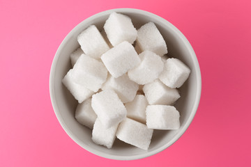Sugar cubes in a bowl on pink background