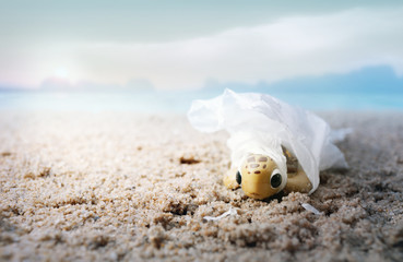 Obraz premium Baby sea turtle tangled in a plastic bag washed. Environmentalism and plastic awareness concept background.