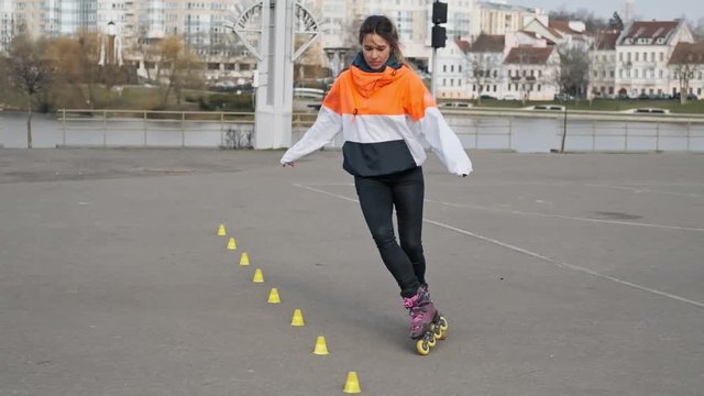 Young stylish girl riding roller skates in slow motion. Girl in park rollerblading.