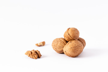 Four whole walnuts and two nutmeats isolated on white background.
