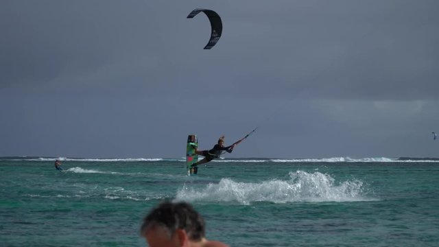 young girl kite surfer riding fast and doing acrobatic tricks.extreme sports kitesurfing in tropical blue ocean,clear beach.pro athlete surfing in mauritius island. filmed in 4K 25fps