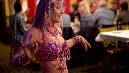 Slow motion extreme closeup of belly dancer doing shoulder chest shimmies in a restaurant.