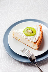 Homemade cottage cheese cake with kiwi fruit and cream on a plate