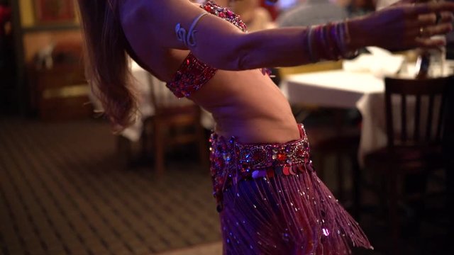 Slow motion closeup of belly dancer&rsquo;s abdomen as she dances in a restaurant.