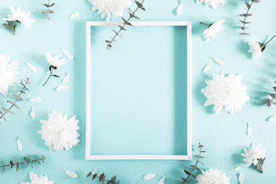 Beautiful flowers composition. Blank frame for text, white flowers, eucalyptus leaves on pastel blue background. Valentines Day, Easter, Happy Women's Day, Mother's day. Flat lay, top view, copy space