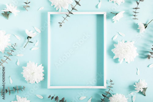 Beautiful flowers composition. Blank frame for text, white flowers, eucalyptus leaves on pastel blue background. Valentines Day, Easter, Happy Women's Day, Mother's day. Flat lay, top view, copy space