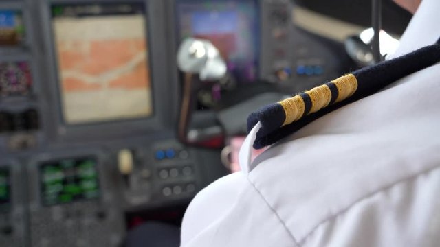 Over shoulder shot co-pilot, first officer flying in private jet aircraft, blurred instrument panel.
