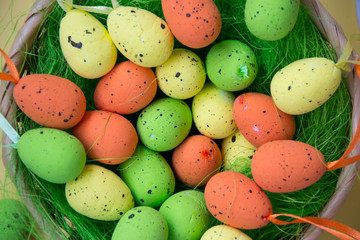 Green nest with colorful Easter eggs decoration on light purple background. Easter concept, holiday tradition top view, close-up image