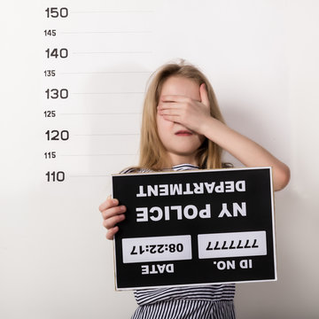 Young beautiful blonde child with a sign covers his face with his hand, Criminal Mug Shots