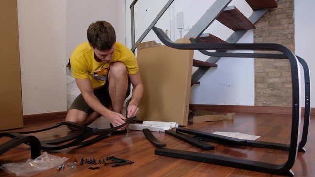 Young man assembles home furniture. Screwing the screws into place.