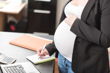 Pregnant woman taking notes at office