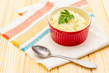 Warm mashed potatoes in a ceramic bowl with fresh parsley. On a vintage linen napkin on a stone background, close up.
