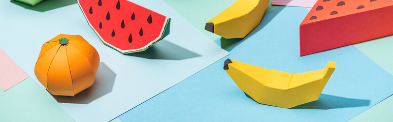 panoramic shot of handmade cardboard fruits on multicolored paper