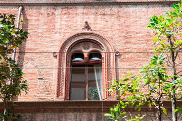 detail of orange house with bow window, curtain  in Bologna, Italy
