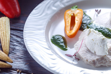 Cooked turkey pieces with cheese and green sauce.