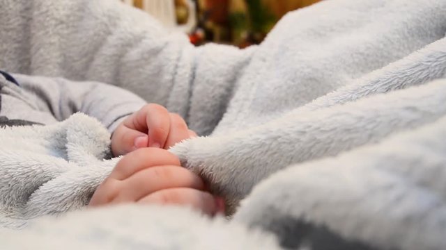 CLOSEUP of a baby's hand holding on to a blanket