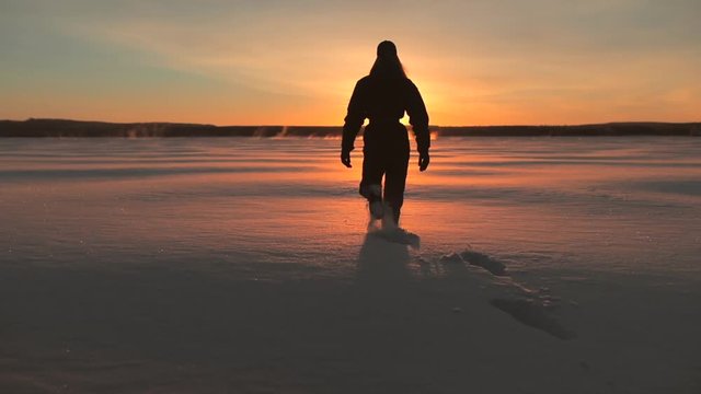 Woman Walking On A Frozen Lake In Sunset.