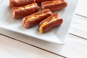 Roasted sausage with yellow cheese over white wooden background
