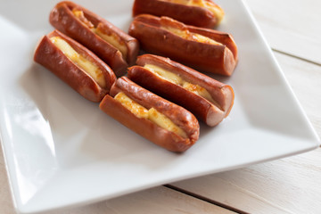Roasted sausage with yellow cheese over white wooden background