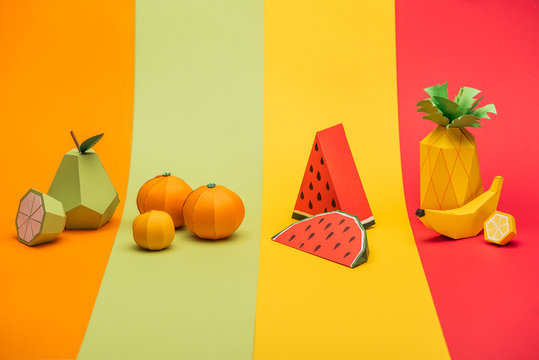 Various handmade origami fruits on stripes of colorful paper