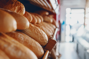 Close up of fresh delicious loafs of bread in row on shelves ready for sale. Bakery interior.