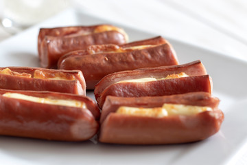 Roasted sausage with yellow cheese over white wooden background