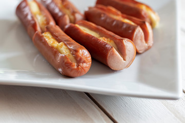 Roasted sausage with yellow cheese over white wooden background