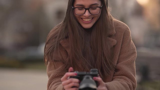 Excited young woman photographing with a mirrorless camera, close up shot